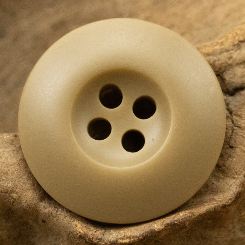 Single khaki 4-hole resin button with four round holes.