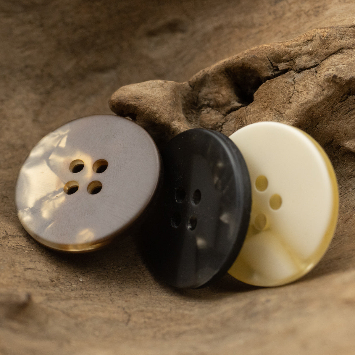 Round 4-hole resin buttons in white, dark gray, and cream tones.