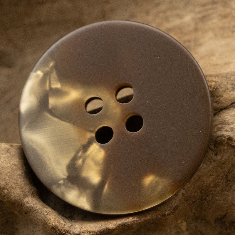 Coffee-brown round resin button with four holes for shirts and coats.