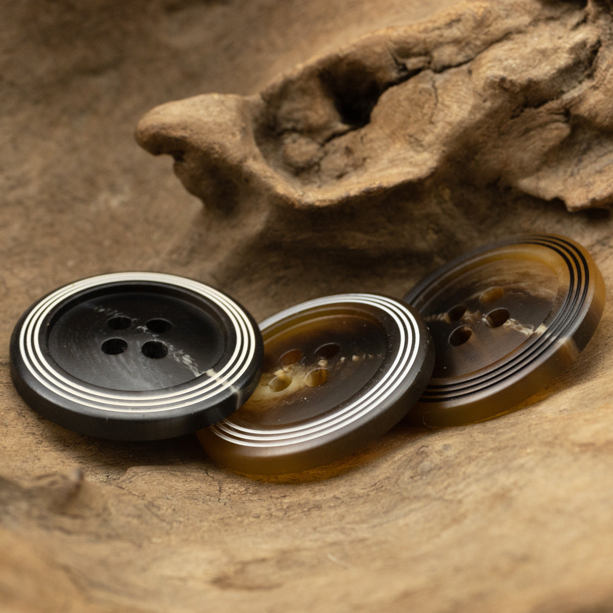 Three matte 4-hole resin buttons with black and white ring stripes