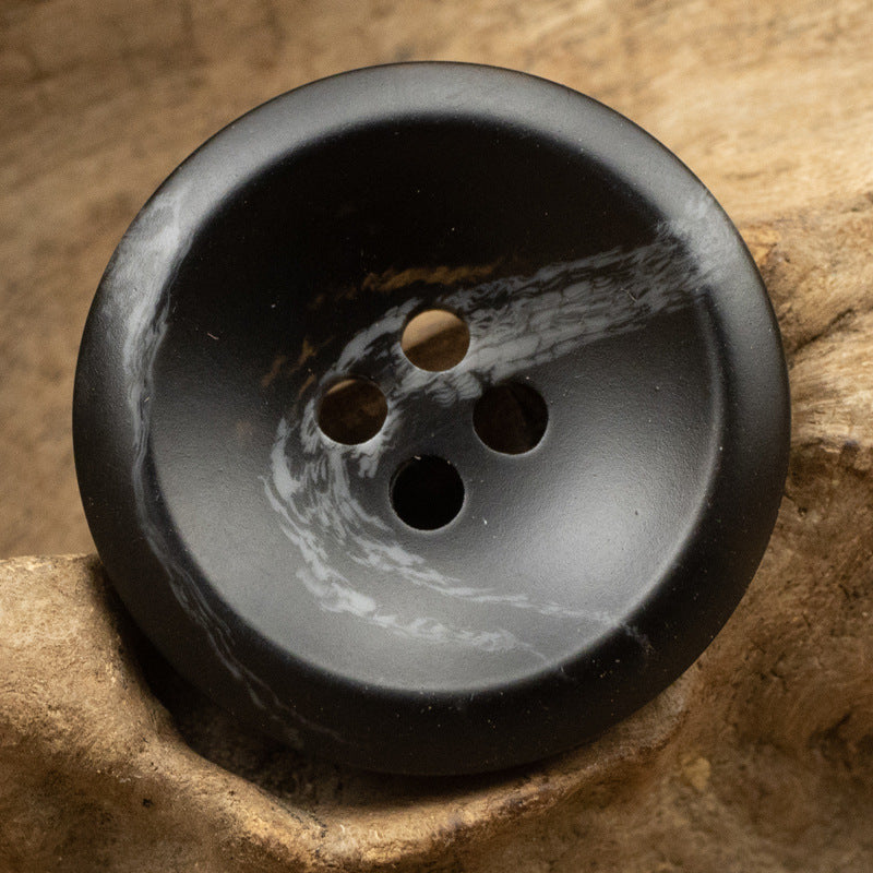Black resin button with white marbled streaks, round 4-hole