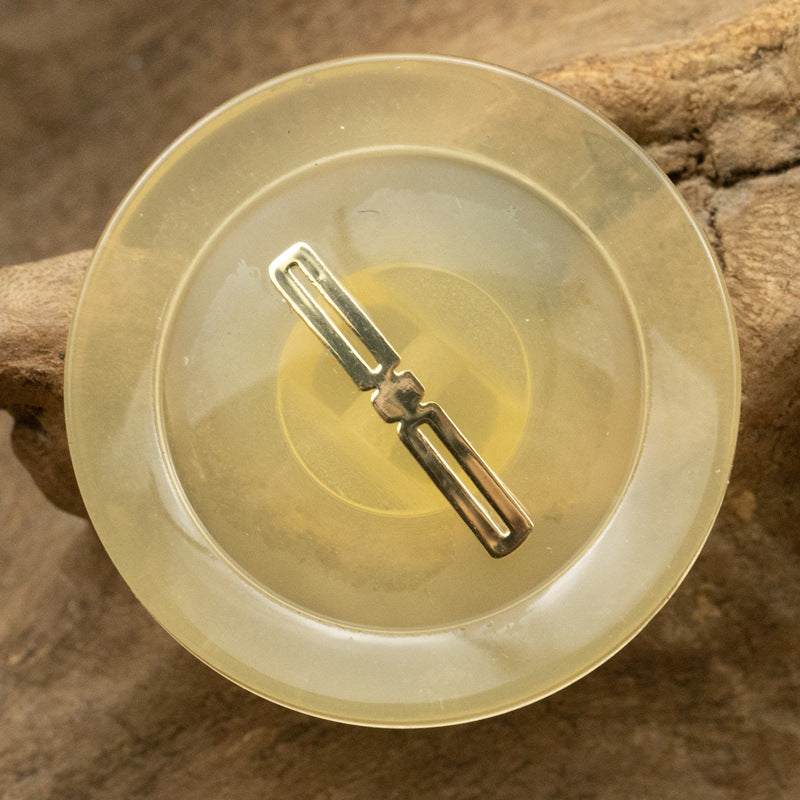 Translucent resin button, light yellow, gold-foil bar center detail (top view)