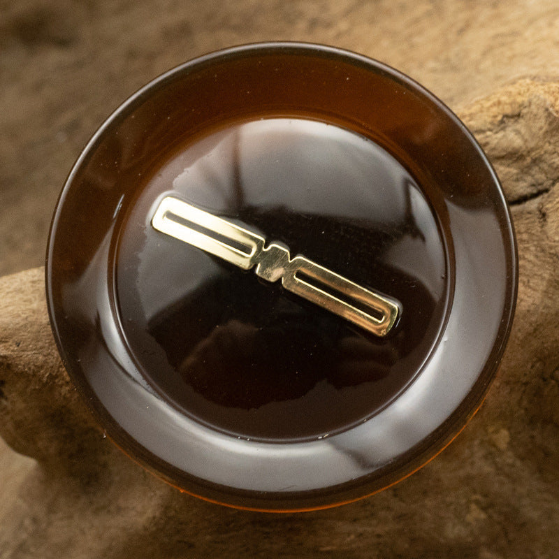 Translucent resin button, red-brown, gold-foil bar center detail