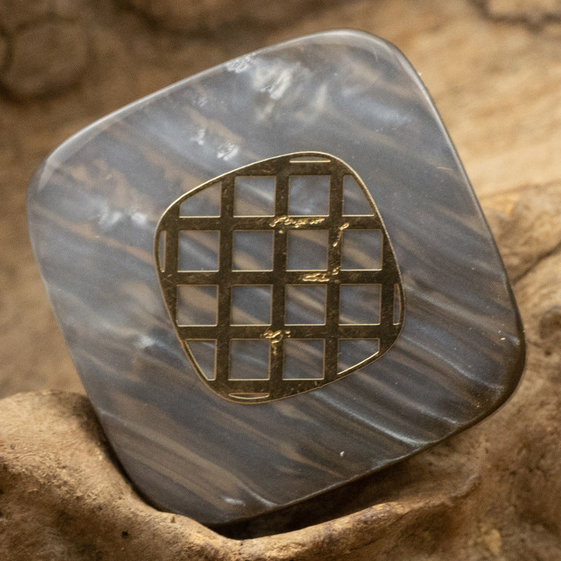 Square resin button in dark grey tone with gold-foil grid design