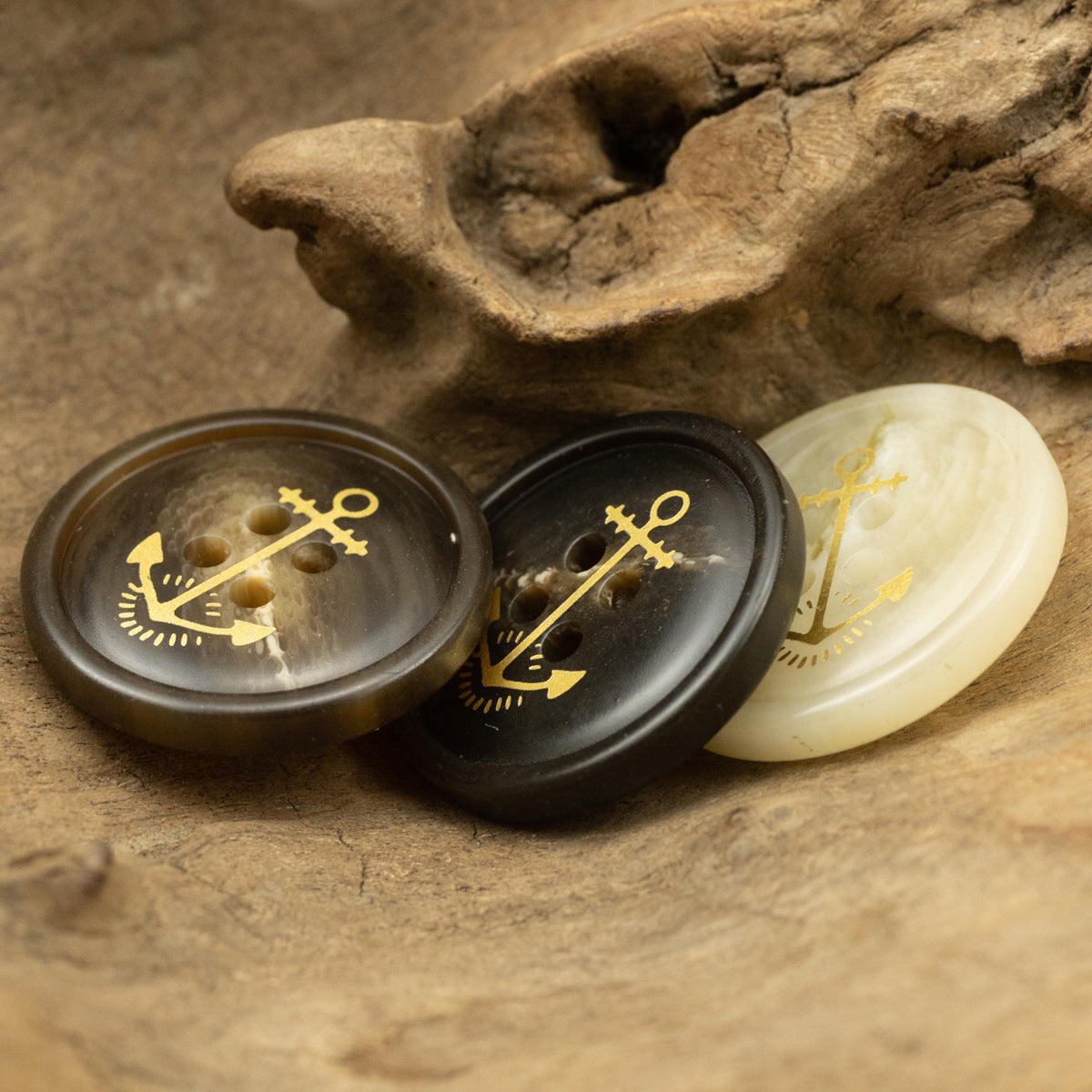 Anchor pattern resin buttons in dark brown and cream, front view with gold nautical anchor