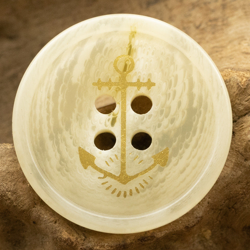 Cream anchor resin button with gold sailor-style anchor motif, 4-hole front view