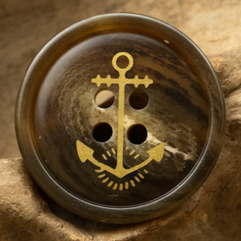 Dark brown anchor resin button with gold nautical anchor design, 4-hole front view