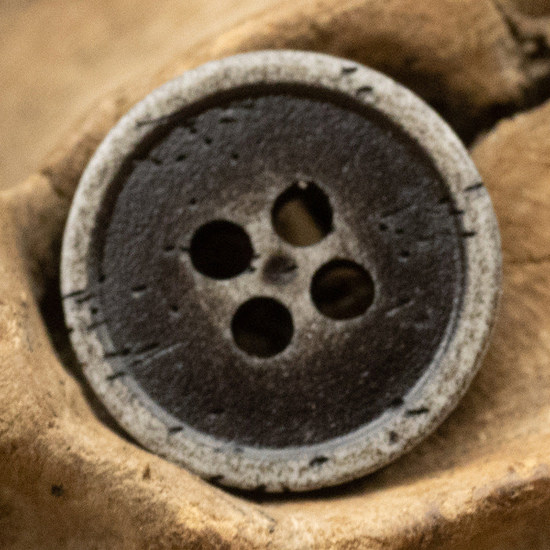 Dark gray distressed resin button with bone-grain look, 4-hole front design.