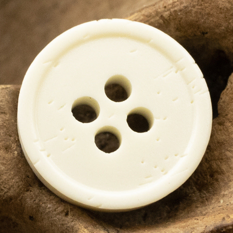 Cream/ivory distressed resin button with 4 holes and bone-grain texture, front view.