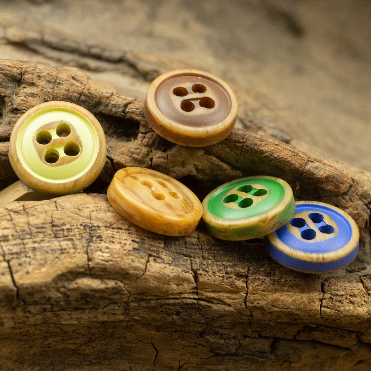 Assorted four-hole resin buttons with painted centers in green, yellow, blue, and natural brown.