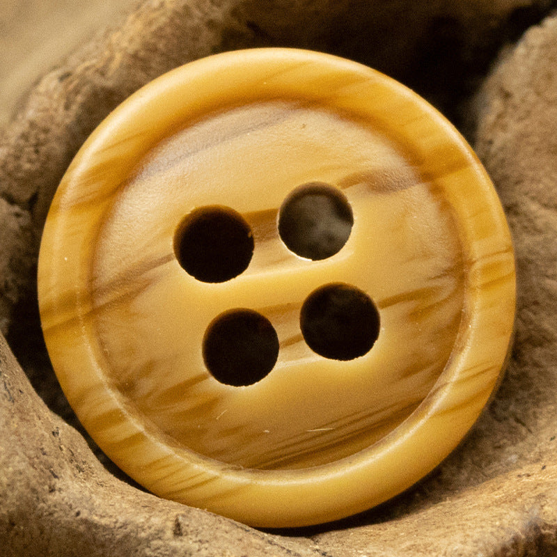 Yellow four-hole resin button with dark holes and a smooth woodgrain outer edge.