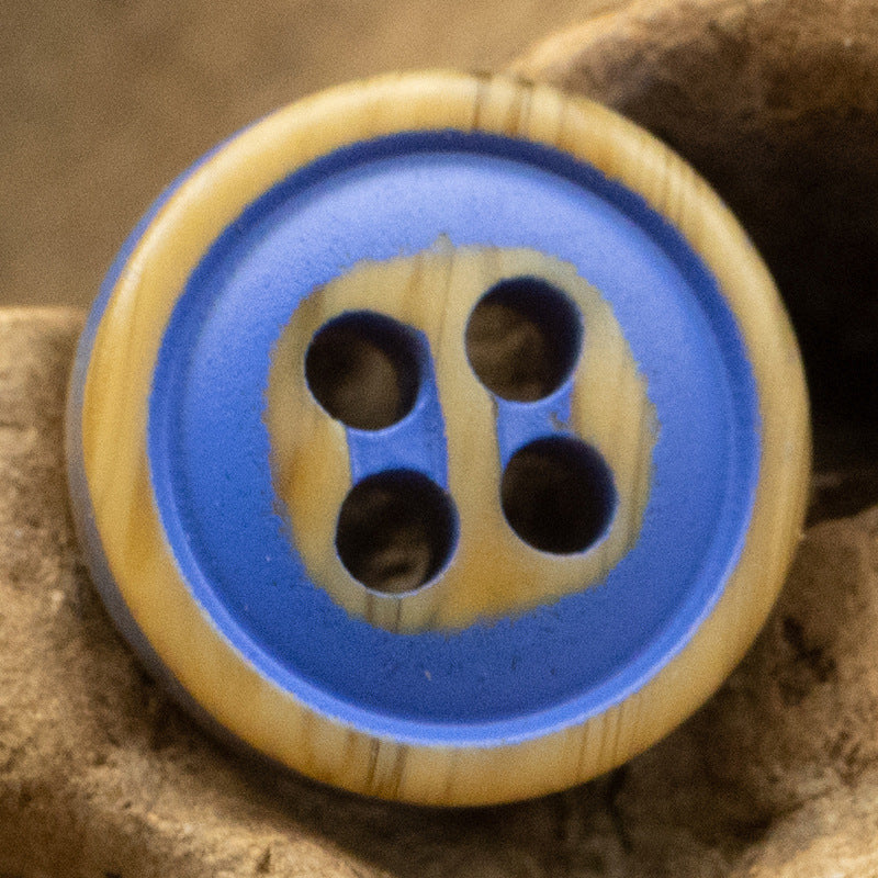 Blue-and-cream four-hole resin button with dark holes and light woodgrain border.