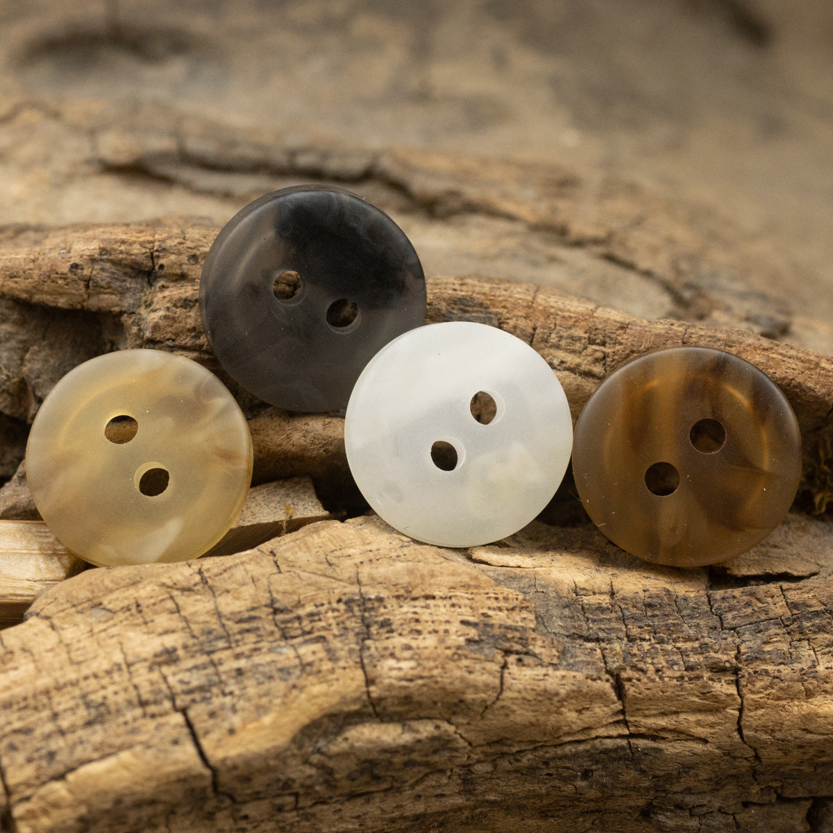 Resin 2-hole buttons in white, dark gray, and brown on wood, three pieces
