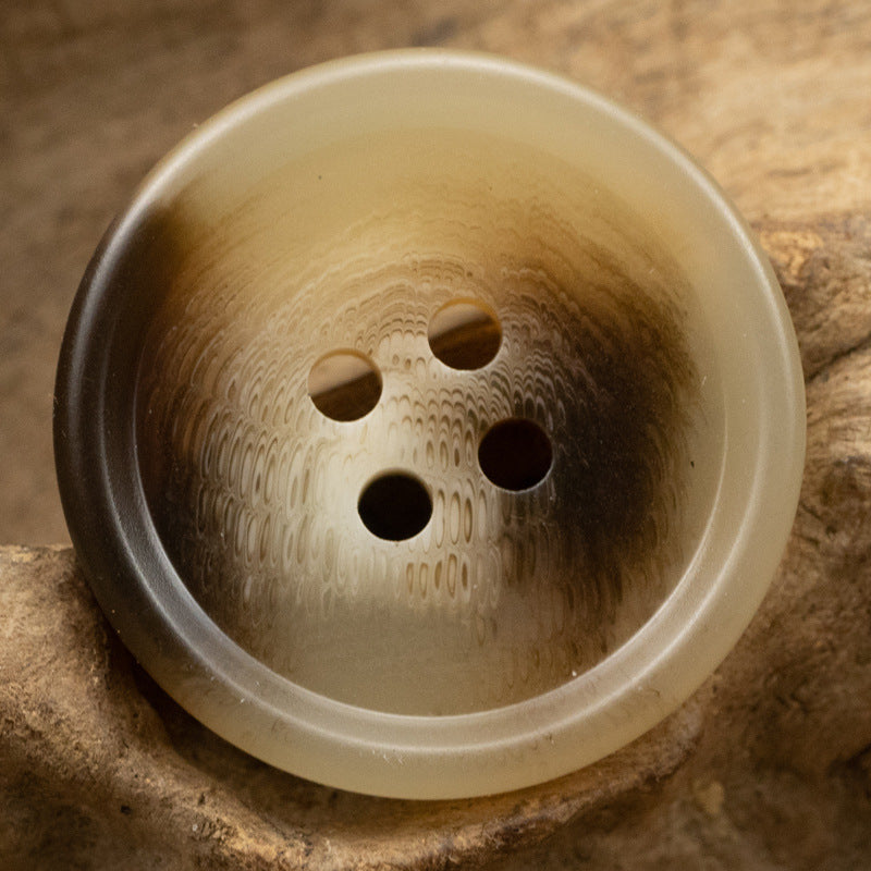 Light tan resin button with four holes and subtle marbled pattern