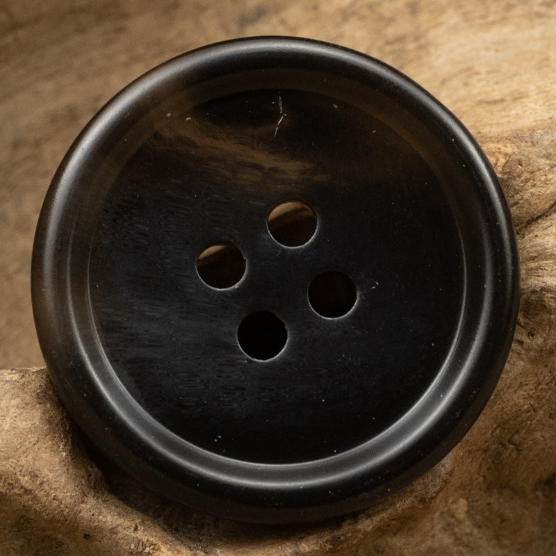 Dark brown/black resin button with four holes, round textured face