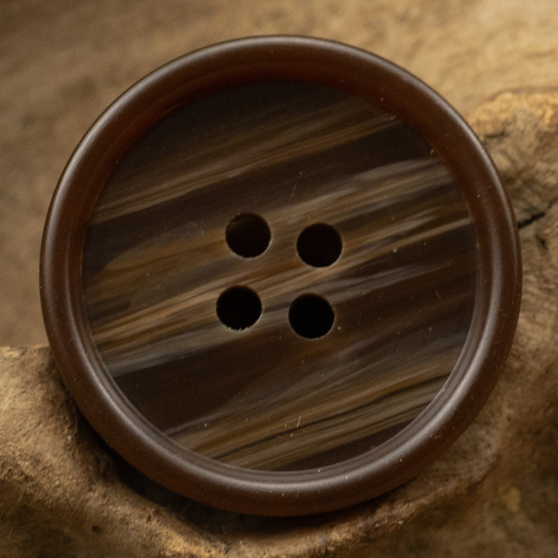 Brown round resin button with 4 holes and visible wood-grain swirls