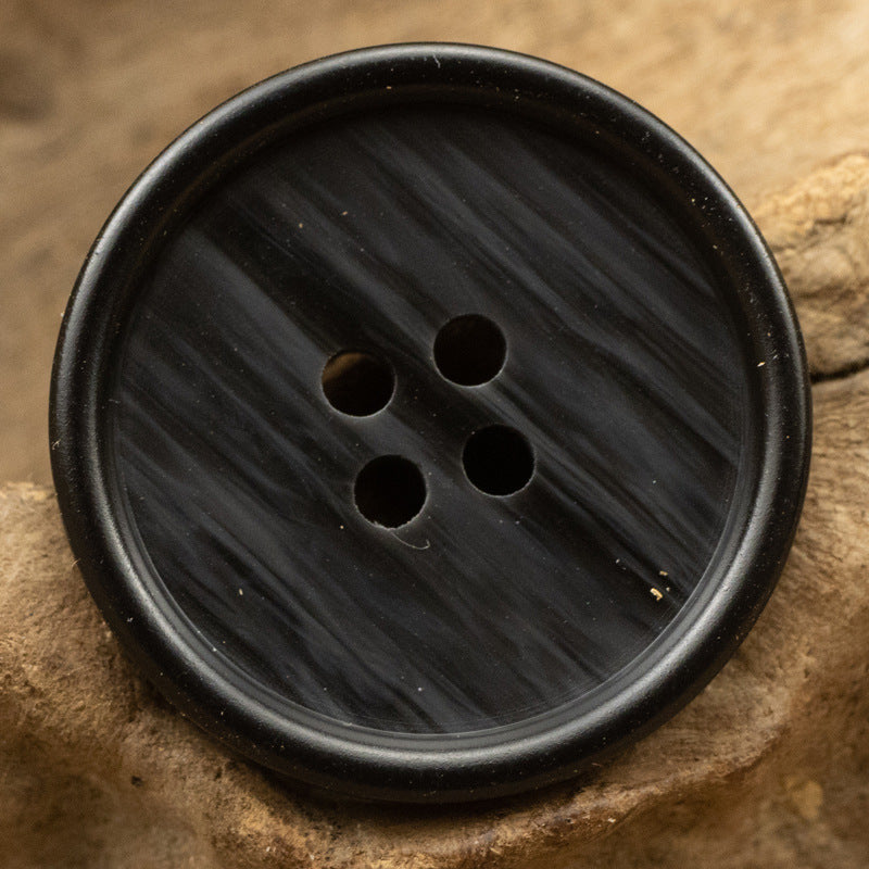 Black round resin button with 4 holes, subtle wood-grain pattern