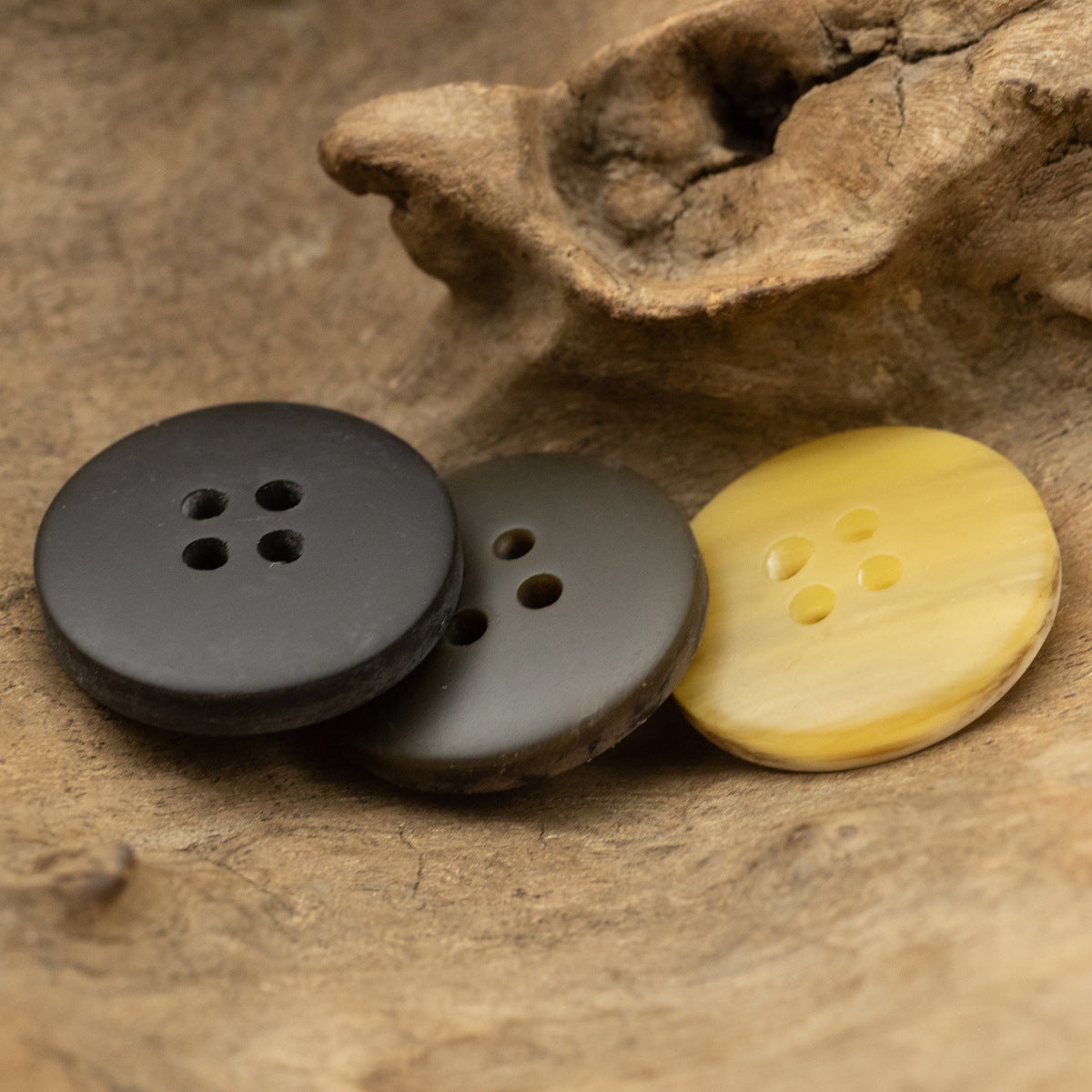 Round resin 4-hole buttons in dark, gray, and pale yellow wood grain