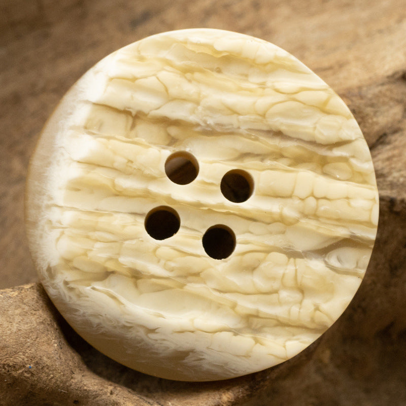 Yellow resin button, irregular round shape with faux tree-bark texture and 4 holes