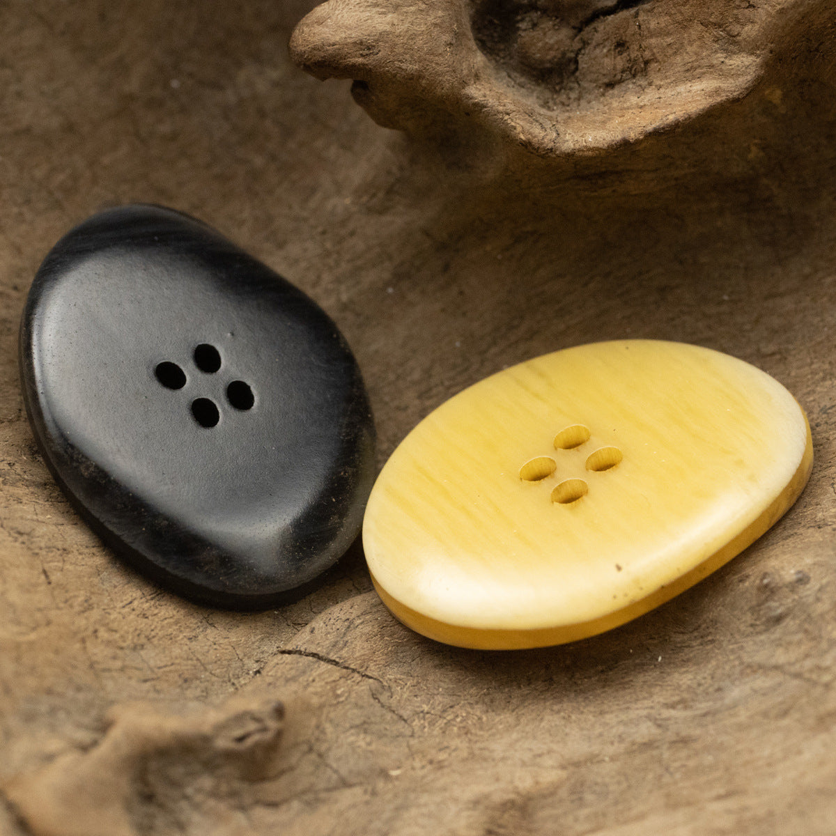 2 large oval resin buttons in black and yellow wood-grain, each with 4 holes