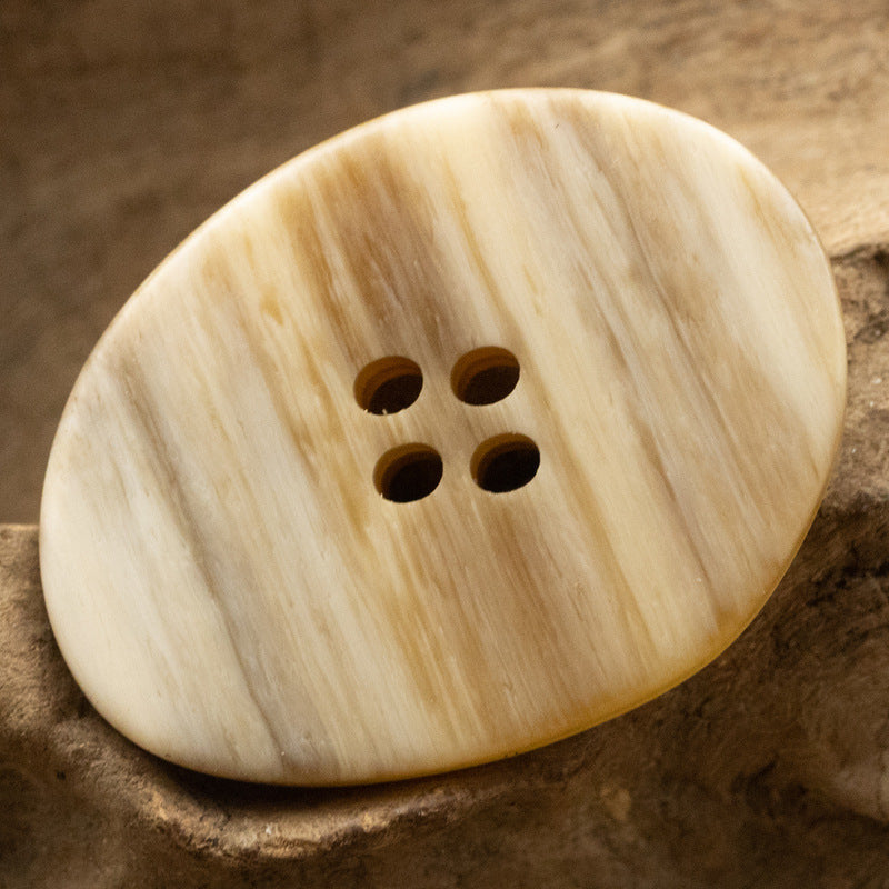 Light yellow cream large irregular oval resin button, wood-grain look, 4-hole close-up