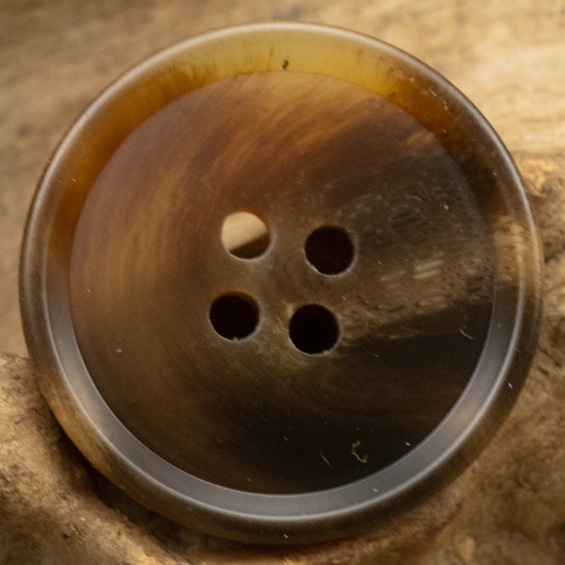 Resin suit button close-up, dark amber-brown, 4-hole front