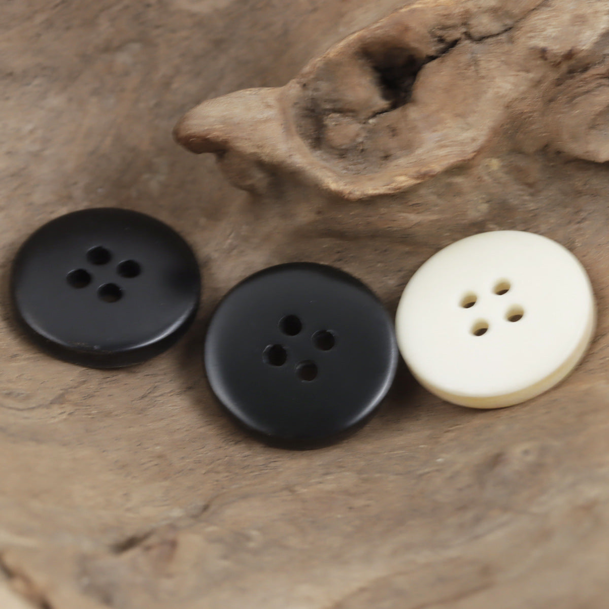 Black and ivory 4-hole round resin buttons with flower-shaped holes