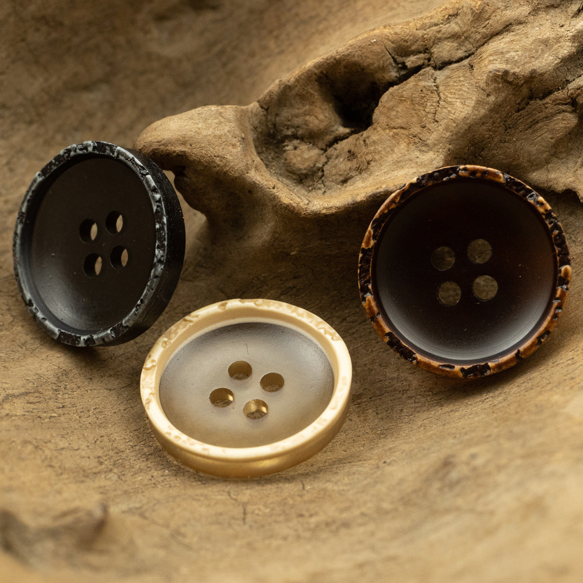 Runde Resin-Knöpfe auf Stein: schwarz, hellbeige und braun, je 4 Löcher