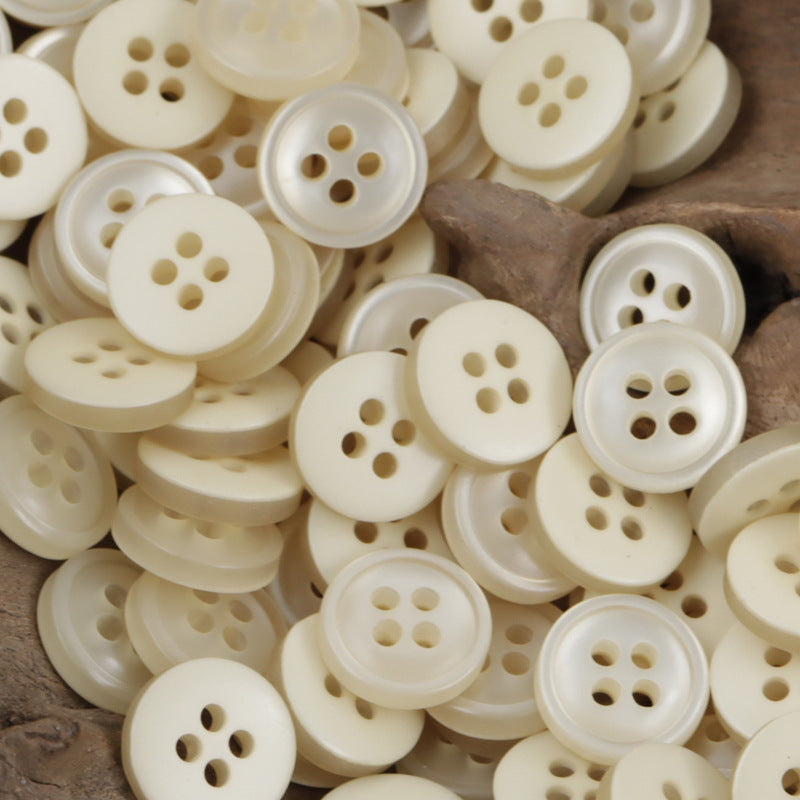 Cream/ivory 4-hole resin buttons, 11.5mm, shown in a dense pile