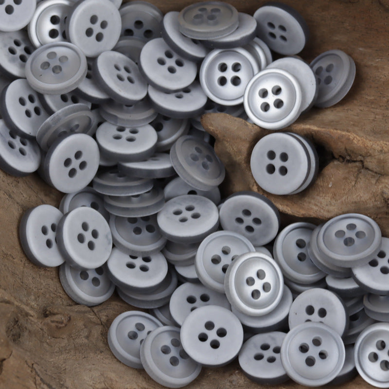 Mixed light and medium gray 4-hole resin buttons, 11.5mm, overlapping in a pile