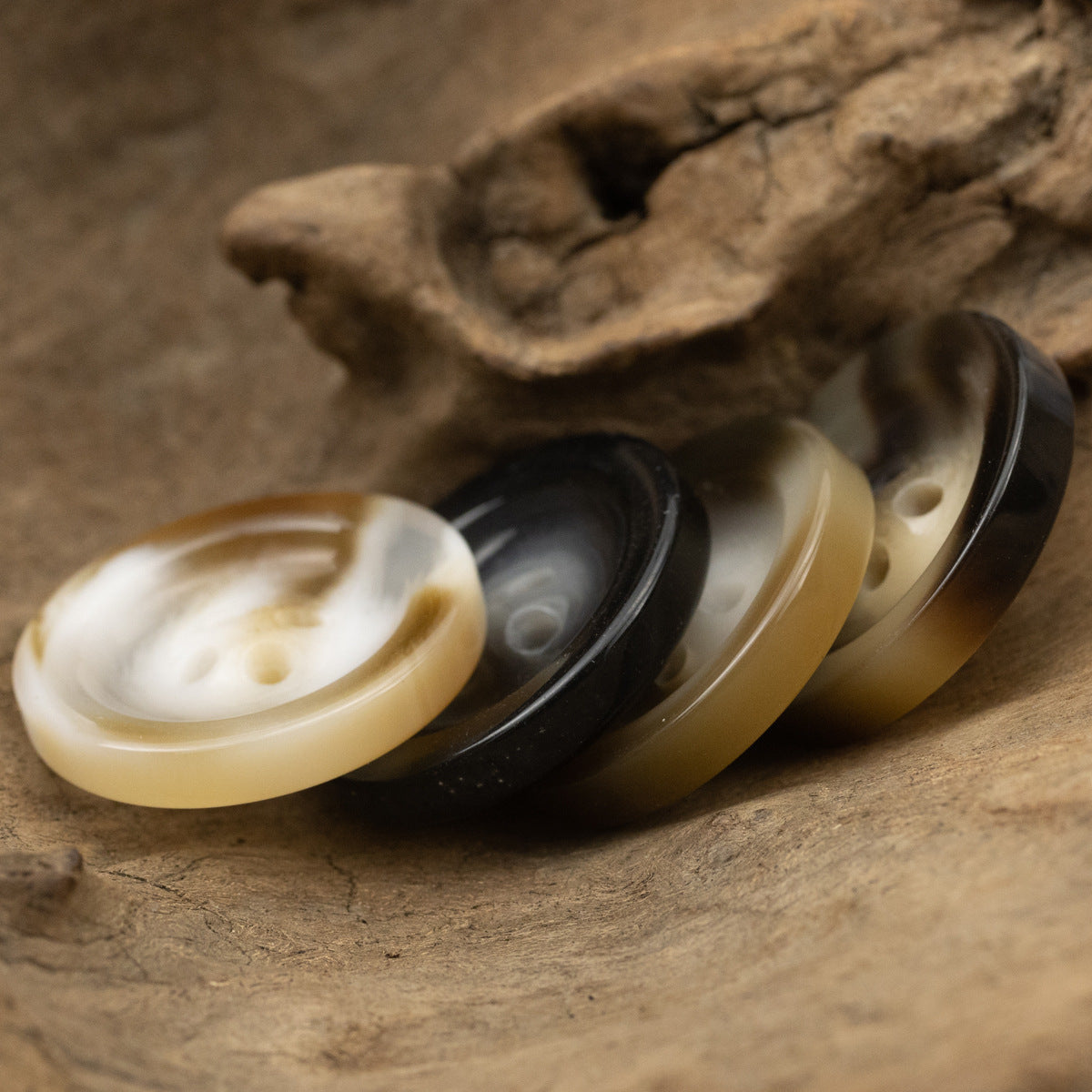 Round 4-hole resin buttons, cream, black, and tan mix with visible holes.