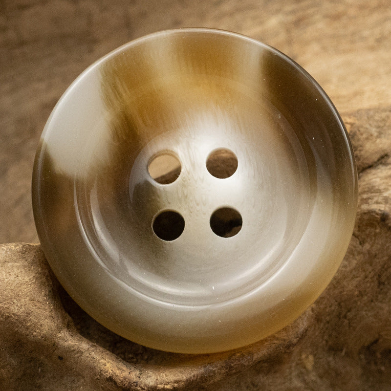 Round 4-hole resin button, translucent honey-tan with dark hole centers.