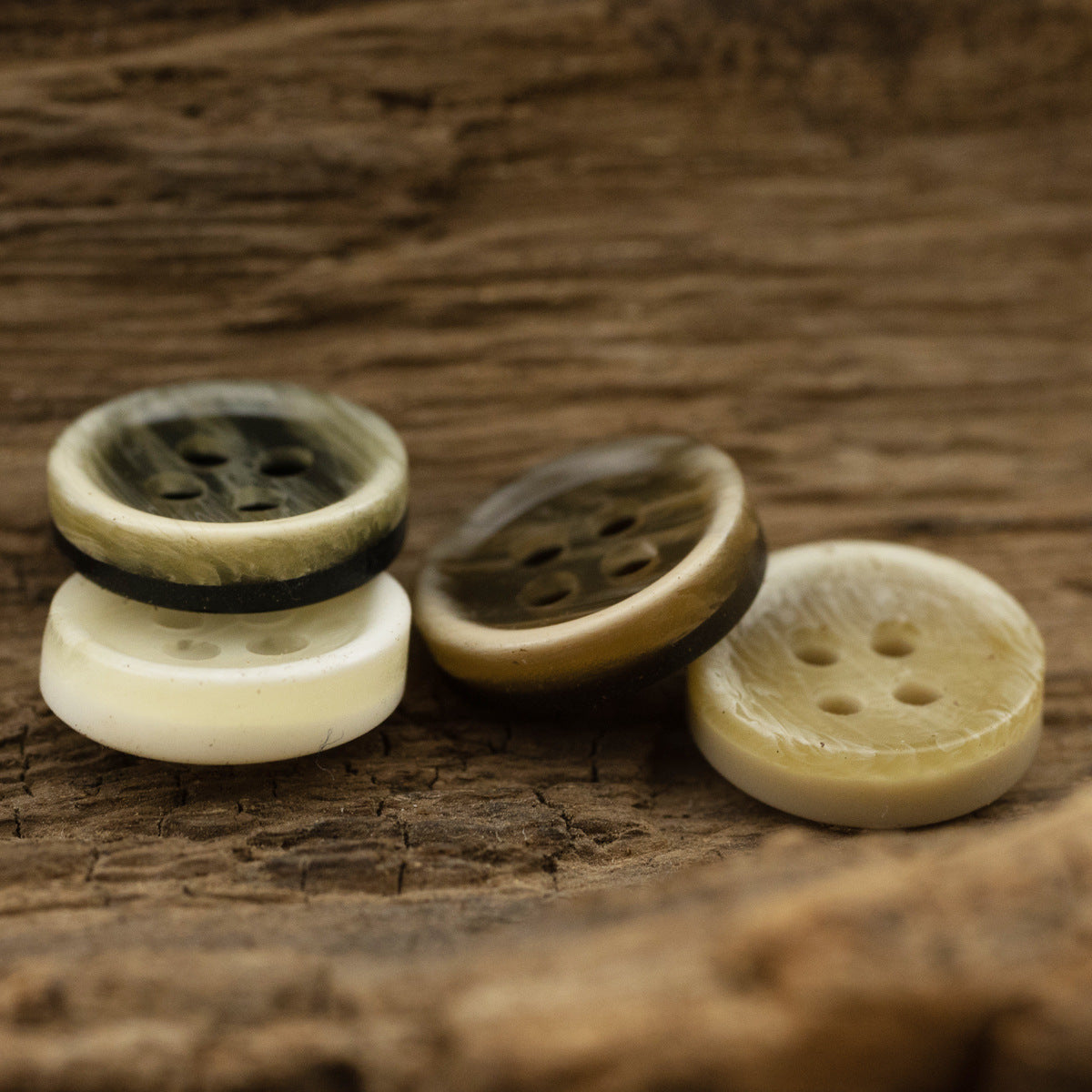 Four resin shirt buttons in cream, tan, and dark colors, each with 4 holes