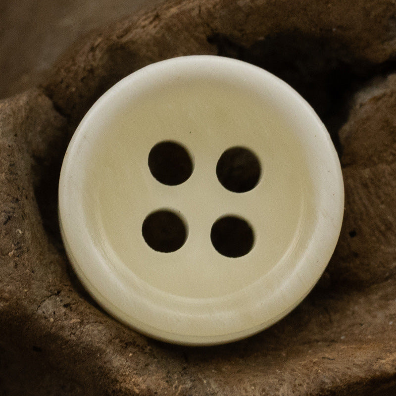 Cream resin shirt button with 4 holes and subtle textured swirl finish