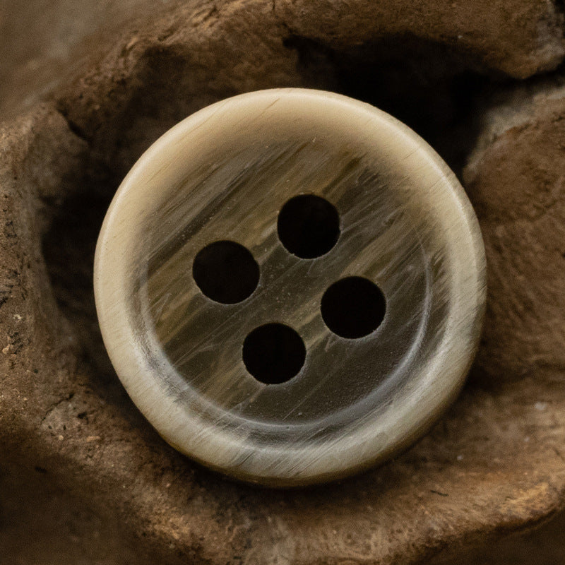 Dark khaki resin shirt button with 4 holes, round textured patterned surface