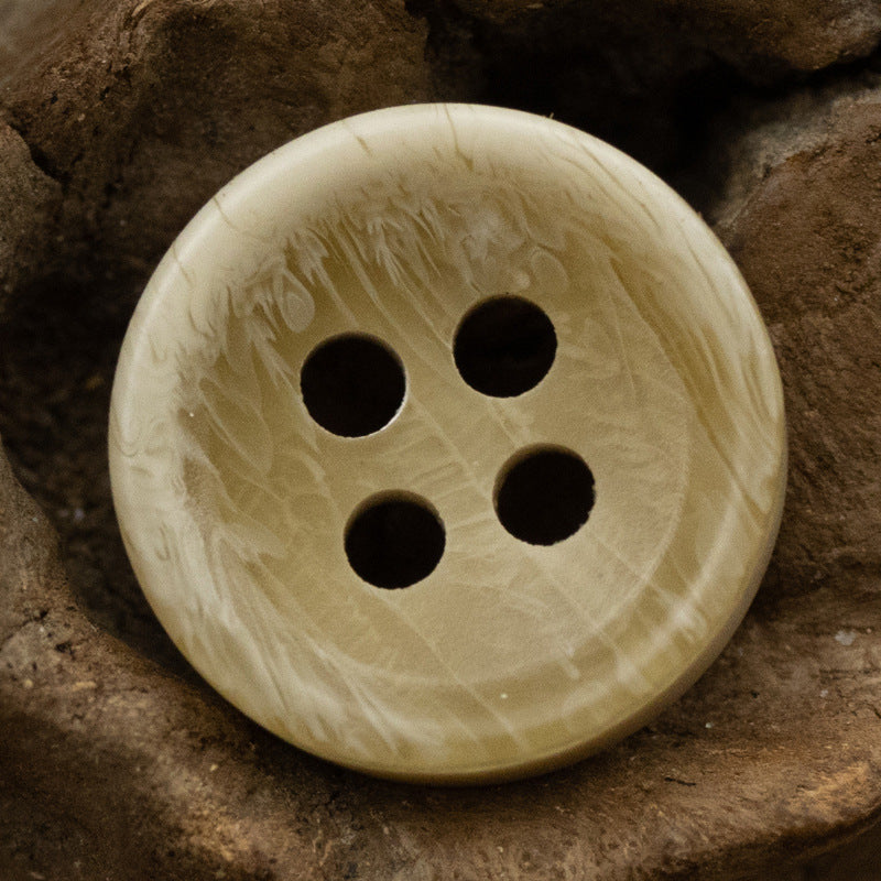 Light cream resin shirt button with 4 holes, glossy textured finish