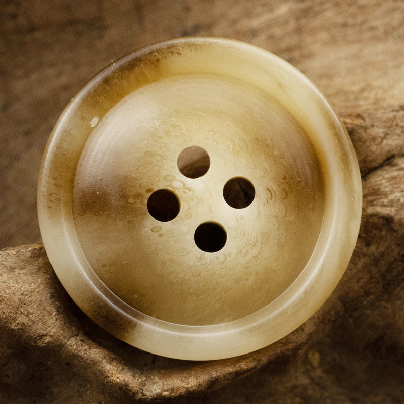 Light off-white resin button with 4 holes, subtle speckled pattern