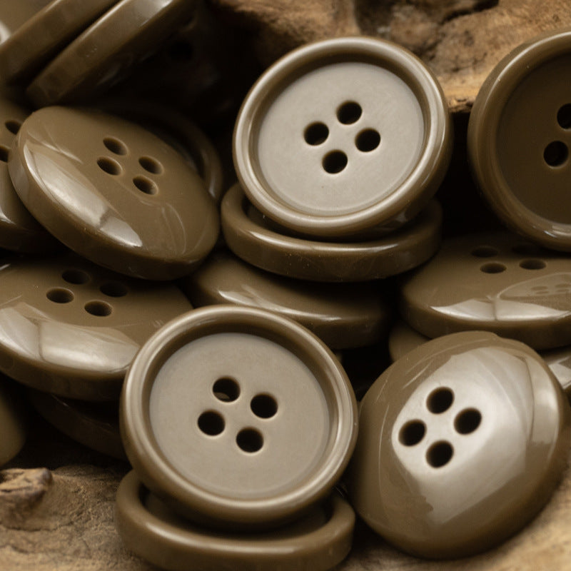 Round four-hole resin buttons in taupe and light beige tones, close-up