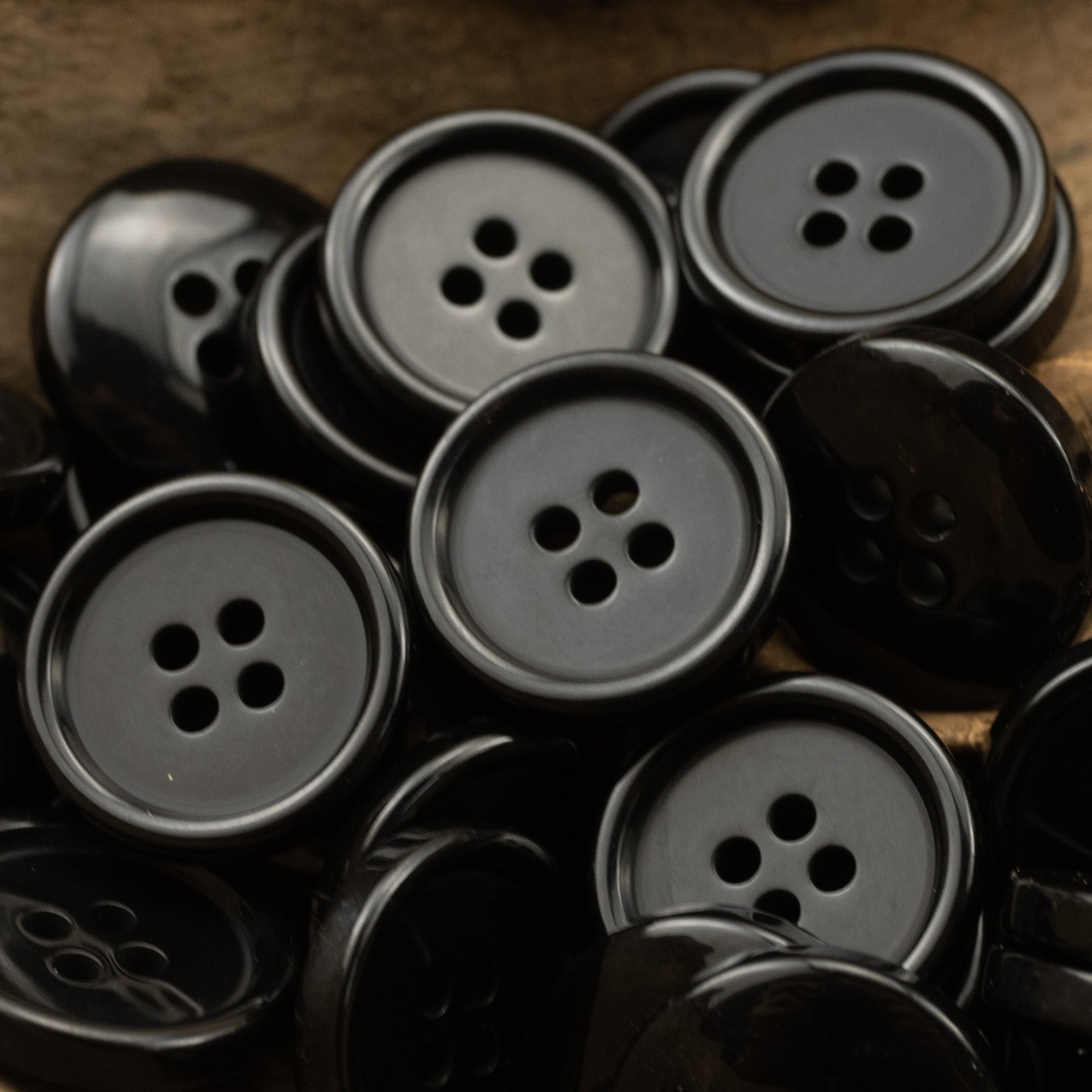 Round four-hole resin buttons in dark gray and black tones