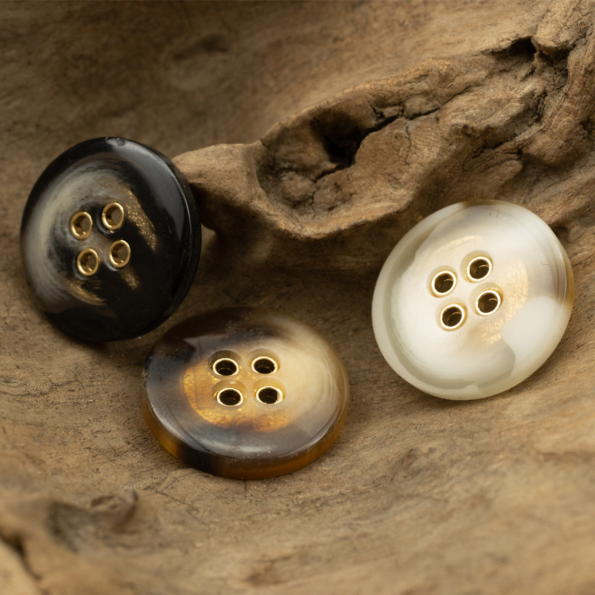 Four-hole round resin buttons with gold rims in black, brown and khaki colors