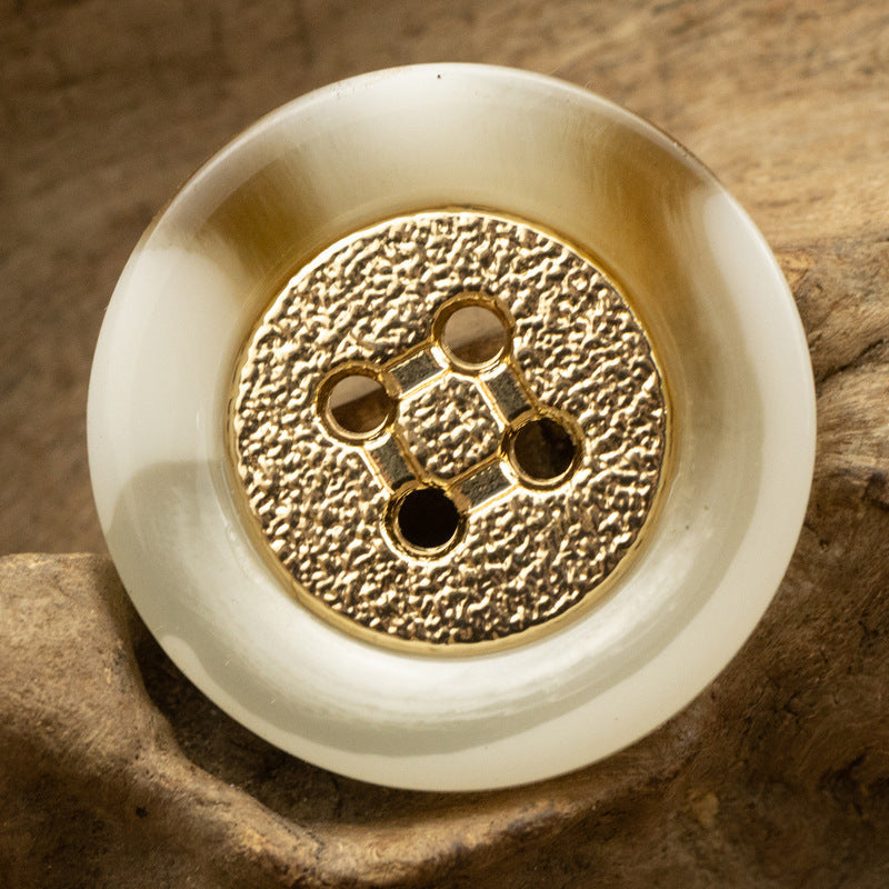 Khaki four-hole round resin button with textured gold center and gold metal rim