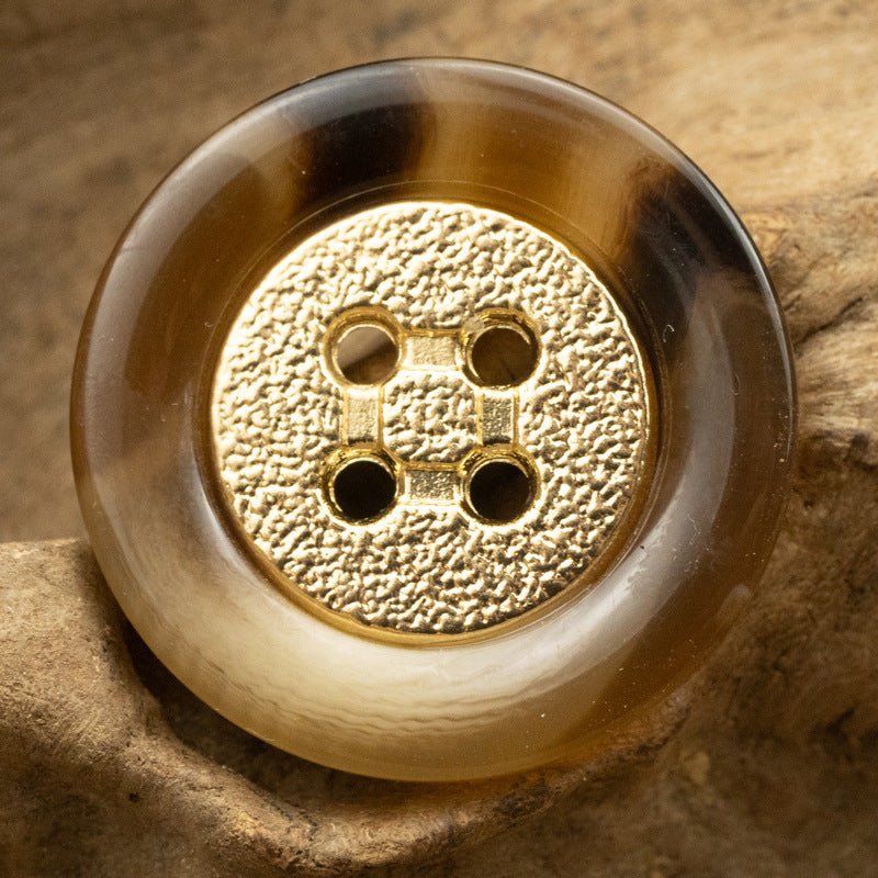 Tan/brown round resin button with gold textured center and gold metal four-hole design