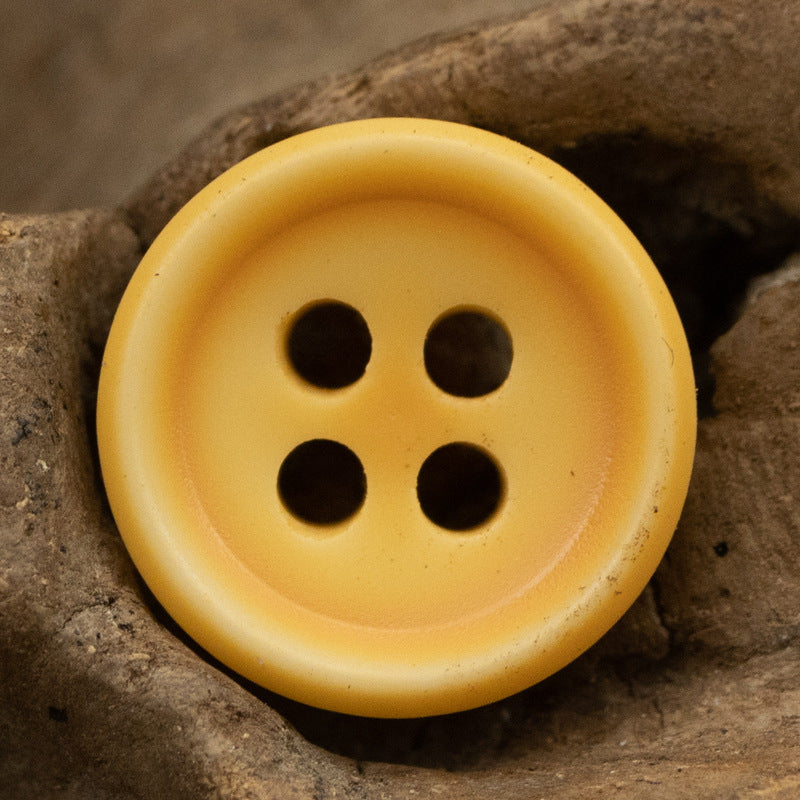 Round orange resin shirt button with four dark holes