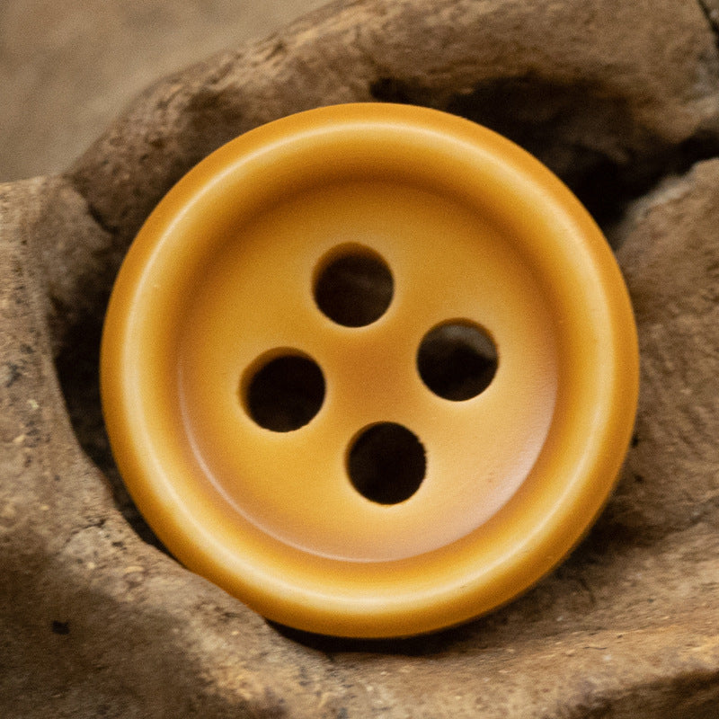 Orange resin button with four holes in a close-up