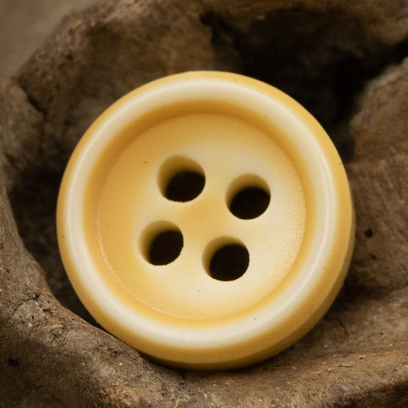 Light orange resin button with four holes, side view