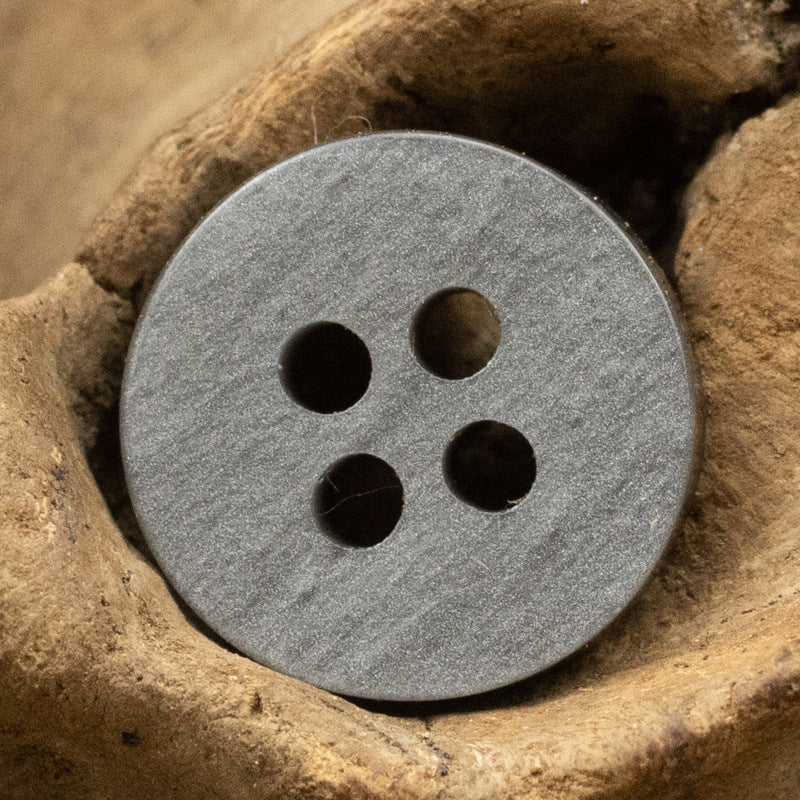 Gray wood-grain resin button close-up, four holes on the face