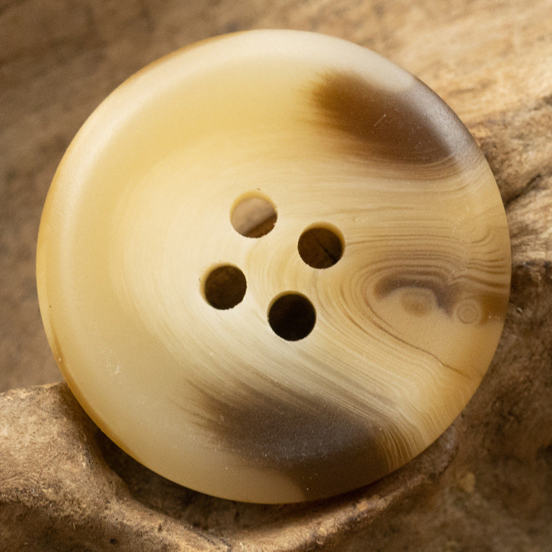 Cream resin button with four holes and warm amber woodgrain, 15–30 mm