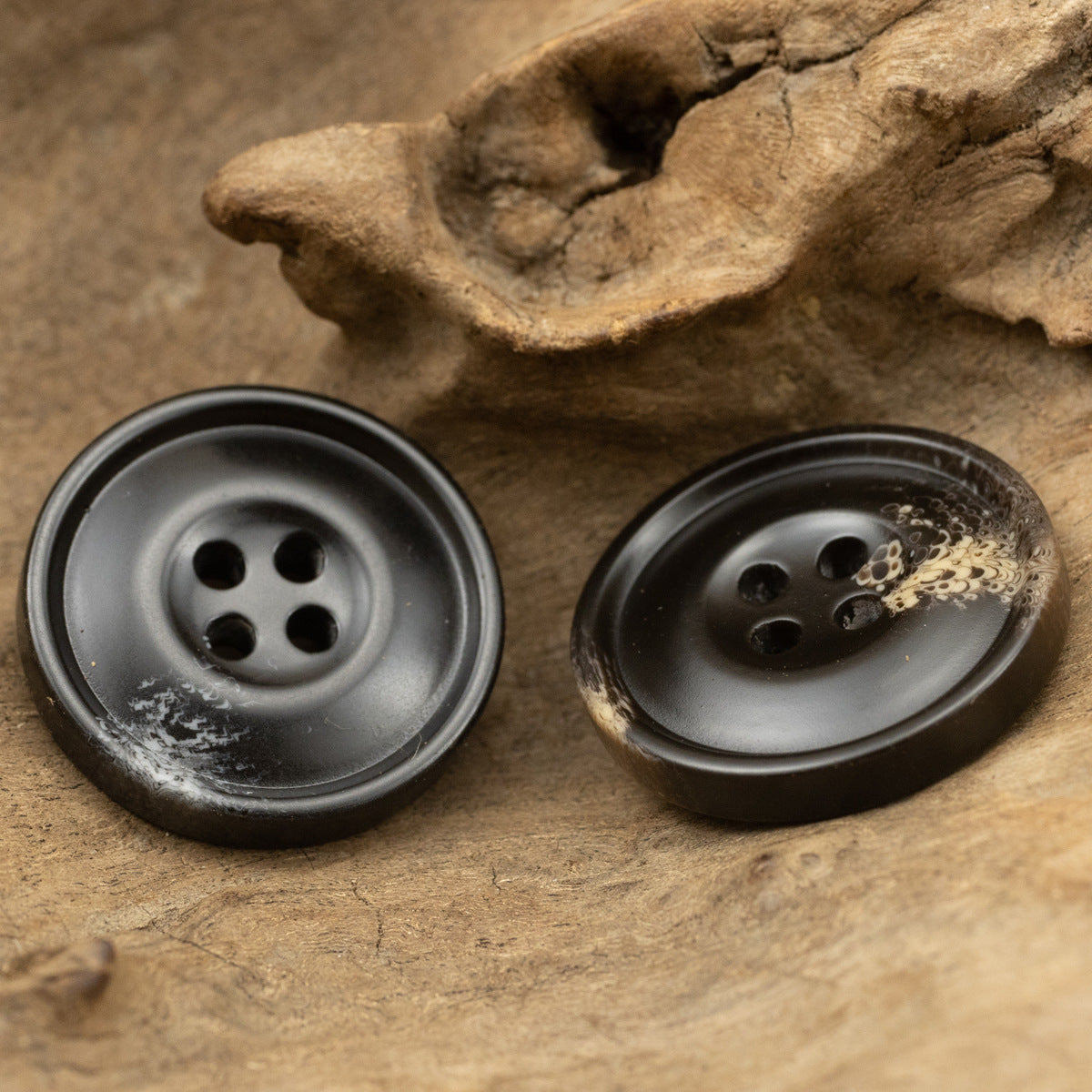 Black resin coat buttons, 4-hole, slight sheen, speckled faces, close-up
