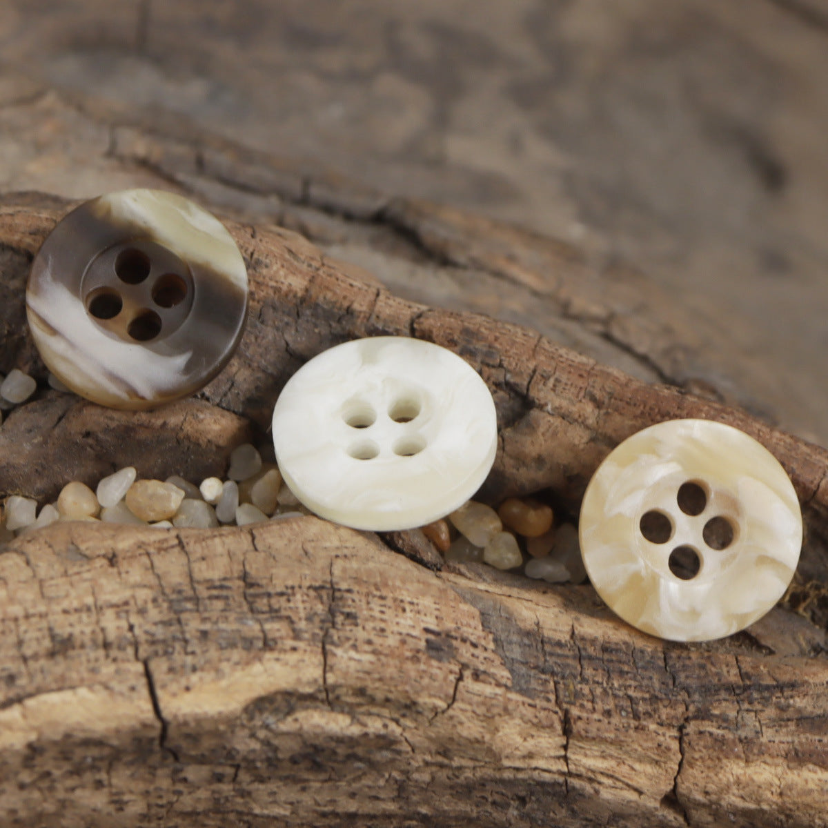 Four-hole resin buttons in mixed cream and dark brown marbling on wood