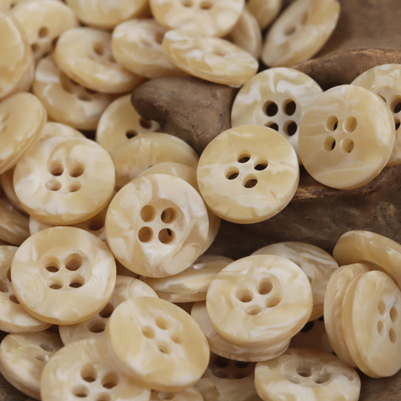 Beige resin buttons with four holes, smooth marbled specks, close-up pile